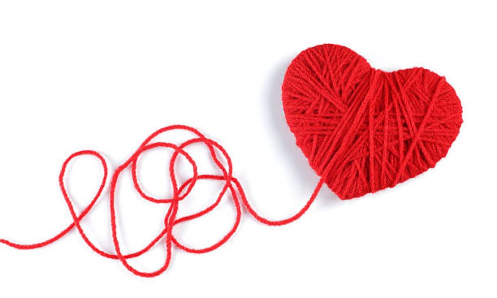 Red heart shape symbol made from wool isolated on white background